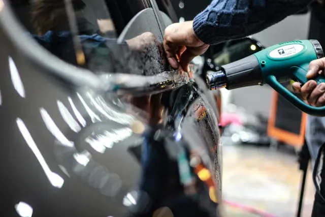 Installer wrapping film around a door edge with a heat gun