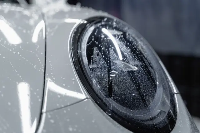 Close-up of a headlight with water beading on protected paint